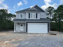 Charming two-story home with gray siding and a two-car garage in a wooded area at 158 Travelers Ct, Lillington, NC 27546