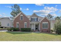 Charming two-story brick home featuring well-manicured lawn, mature trees and classic architectural details at 55 Blue Pine Dr, Spring Lake, NC 28390