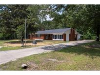 Charming brick home with mature trees, a well-maintained lawn, and a long driveway at 5824 Adcock Rd, Holly Springs, NC 27540