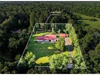 Spacious lot featuring a home with a red roof, surrounded by lush greenery and mature trees at 602 Canterbury Rd, Sanford, NC 27330