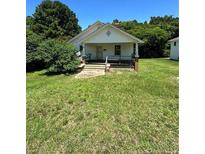 Charming single-story home with a gable roof and covered front porch, surrounded by green lawn and mature trees at 410 W K St, Erwin, NC 28339
