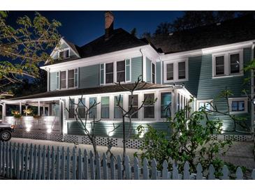 Charming two-story home featuring a cozy front porch, crisp white trim and manicured landscaping at night at 304 15Th W St, Bradenton, FL 34205