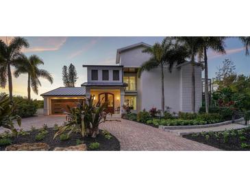 Luxury two-story home with landscaped grounds, a metal roof, and a brick paver driveway at 6934 Belgrave Dr, Sarasota, FL 34242