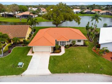 Single-story home with orange tile roof, large yard, and water view at 1654 Waxwing Ct, Venice, FL 34293