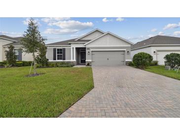 House exterior featuring a two-car garage and well-manicured lawn at 19642 Fort King Run, Brooksville, FL 34601