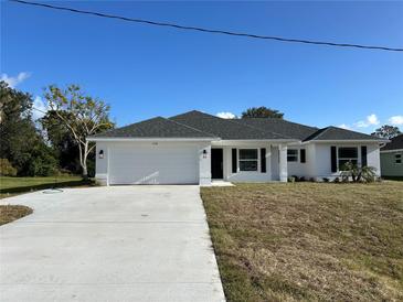 Newly constructed home with a white exterior, gray roof, and a two-car garage at 2738 N Chamberlain Blvd, North Port, FL 34286