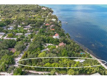 Aerial view of waterfront property with lush landscaping and tennis court at 3301 Bay Shore Rd, Sarasota, FL 34234