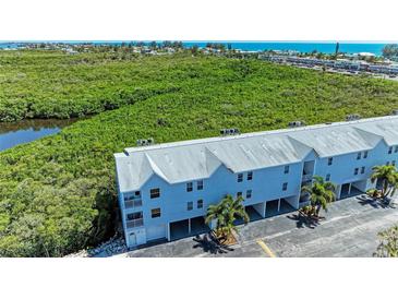A condo with views, a light gray roof, palm trees, and an open space underneath at 3607 E Bay Dr # 202, Holmes Beach, FL 34217