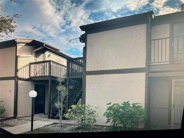 Two-story condo featuring neutral stucco, dark trim, wooden balconies, and manicured shrubbery at 4022 Beaver Ln # 1000G, Port Charlotte, FL 33952