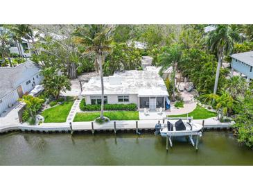 Aerial view of waterfront home with boat lift and lush landscaping at 562 Juan Anasco Dr, Longboat Key, FL 34228