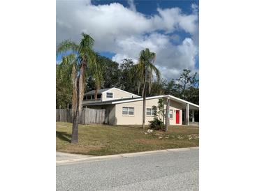 Tan single-story home with red door, palm trees, and fenced yard at 3375 8Th St, Sarasota, FL 34237
