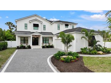 Stunning two-story home featuring a manicured lawn, beautiful landscaping, and a stylish black and white color scheme at 1783 Bayview Dr, Sarasota, FL 34239