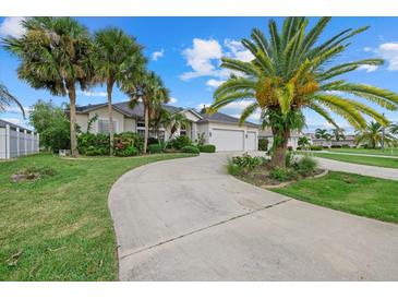 Two-story house with a circular driveway, palm trees, and a two-car garage at 974 Rotonda Cir, Rotonda West, FL 33947