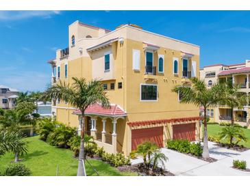 Beautiful three-story yellow home with two-car garage, lush landscaping, and a red tile roof at 1450 Silvia Shores Dr, Apollo Beach, FL 33572