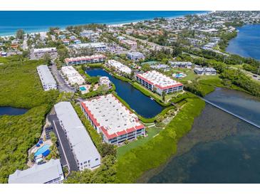 Aerial view of waterfront community with lush landscaping, tennis courts, and a pool at 3705 E Bay Dr # 115, Holmes Beach, FL 34217