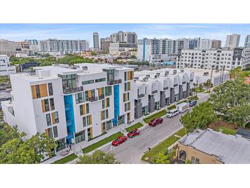 Modern townhomes featuring colorful accents line a city street with lush trees and parked vehicles at 1558 4Th St # 216, Sarasota, FL 34236