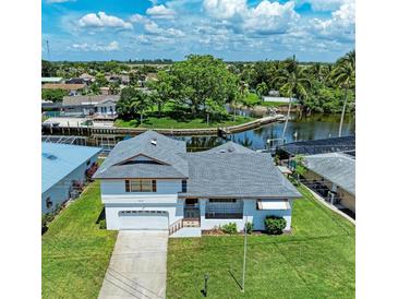 Aerial view of canal-front home with lush landscaping and two-car garage at 5111 Coral Blvd, Bradenton, FL 34210