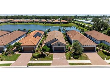 Beautiful single-story home with a well-maintained lawn, brick driveway, and barrel tile roof near a tranquil pond at 5709 Puccini St, Nokomis, FL 34275