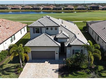 Two-story home with gray tile roof, paver driveway, and landscaping at 5713 Cheech Gln, Lakewood Ranch, FL 34211