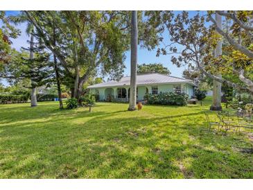 Ranch home with lush lawn, mature trees, and a metal roof at 2403 Palma Sola Blvd, Bradenton, FL 34209