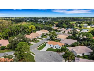 Scenic aerial view of a quiet residential neighborhood with lush greenery and well-maintained homes, and distant views of the water at 2128 Waweep Ct, Sarasota, FL 34235