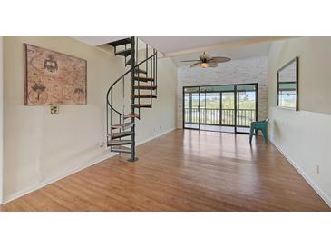 Bright living room features a spiral staircase and sliding glass doors leading to a beautiful outdoor view at 1026 Bird Bay Way # 276, Venice, FL 34285