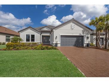 Charming single-story home featuring a brick driveway, gray door, and two-car garage at 5510 Panella Ct, Palmetto, FL 34221