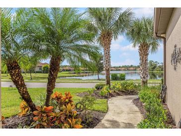 Walkway leads to a pond view, lush landscaping, and palm trees at 212 Casalino Dr, Nokomis, FL 34275