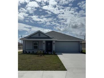 Charming single-story home featuring a two-car garage and a well-manicured lawn under a sunny, partly cloudy sky at 2628 Averland Loop, North Port, FL 34287