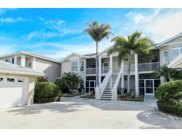 Beautifully landscaped two-story condo with pristine sidewalks and manicured bushes at 111 Woodbridge Dr # 202, Venice, FL 34293