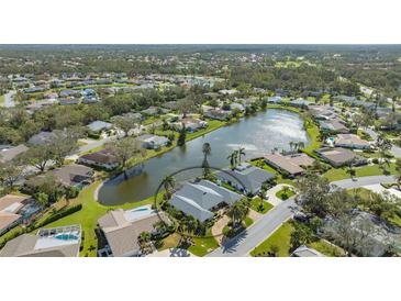 Aerial view of single-Gathering home on a lake with lush landscaping at 5692 Country Lakes Dr, Sarasota, FL 34243