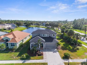 Beautiful two-story home featuring a lake view, manicured lawn, and a spacious driveway at 1868 Scarlett Ave, North Port, FL 34289