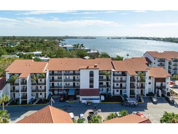 Aerial view of waterfront condo building with parking and landscaping at 1624 Stickney Point Rd # 401, Sarasota, FL 34231