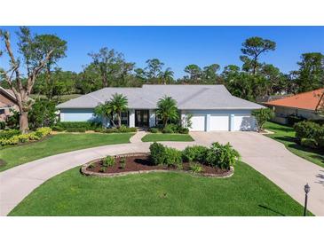 Single-story home with a three-car garage and landscaped yard at 7917 Broadmoor Pines Blvd, Sarasota, FL 34243