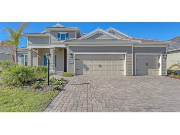 Two-story house with light beige siding, three-car garage, and landscaped yard at 21205 Holmes Cir, Venice, FL 34293