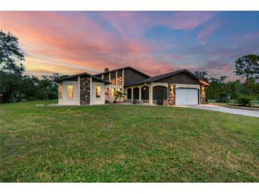 Stunning home boasts unique architectural details, stone accents, and a well-manicured lawn, creating a captivating curb appeal at 220 Ciboa Ave, North Port, FL 34287