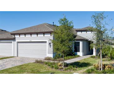 Two-car garage, gray exterior, landscaped yard, and a paved driveway at 12513 Oak Hill Way, Parrish, FL 34219