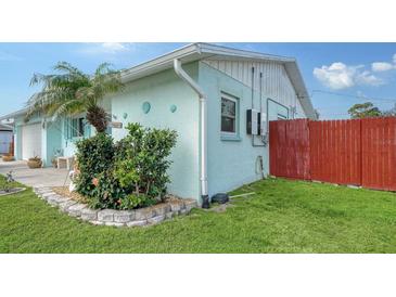 Charming home featuring a well-maintained lawn, vibrant flower beds, and a colorful red fence for added curb appeal at 1080 Piedmont Rd, Venice, FL 34293