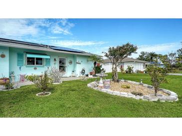 Charming Florida home with a well-manicured lawn, colorful landscaping, and solar panels at 1080 Piedmont Rd, Venice, FL 34293