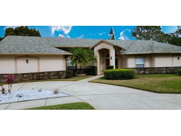 Tan two-story house with grey roof, landscaping, and a long driveway at 15903 Armistead Ln, Odessa, FL 33556