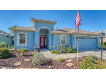 Single-story home with red door, landscaped yard, and attached garage at 10643 Old Grove Cir, Bradenton, FL 34212