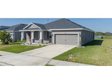 Single-story home with gray siding, two-car garage, and landscaped lawn at 16128 67Th E Ct, Parrish, FL 34219