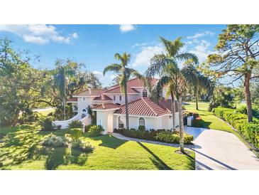 Stunning two-story home boasts lush landscaping, a red tile roof, and a circular driveway at 401 Walls Way, Osprey, FL 34229