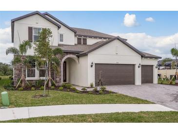 Two-story house with stone accents, three car garage, and landscaped yard at 5554 Sand Fossil Ct, Sarasota, FL 34238