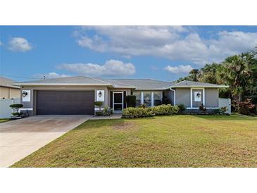 Single-story home with gray exterior, attached garage, and landscaped lawn at 6261 Keating Ave, North Port, FL 34291