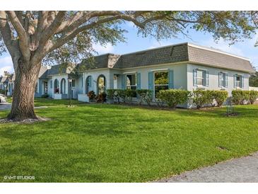 Light blue house with gray roof, spacious lawn, and large tree in front at 4009 38Th Avenue W Dr # 4009, Bradenton, FL 34205