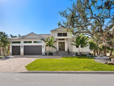 Two-story home with a three-car garage, stone accents and lush landscaping at 616 Mangrove Point Rd, Siesta Key, FL 34242