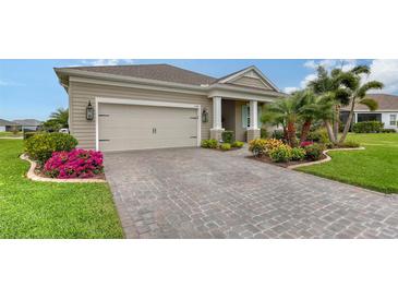 Tan house with landscaped yard, paver driveway, and two-car garage at 13789 Old Creek Ct, Parrish, FL 34219