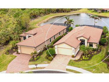 Two-story homes with tile roofs and attached garages, near a lake at 1342 Calais Cir, North Venice, FL 34275