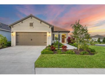 Single-story home with a two-car garage, landscaped yard, and sunset view at 12735 Aquamarine Ave, Bradenton, FL 34211